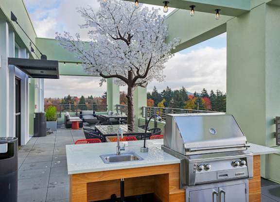 A patio with a grill and a tree with white blossoms.