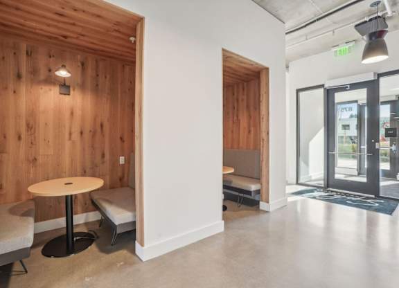 A room with a wooden wall and a white pillar with a round table and two chairs.