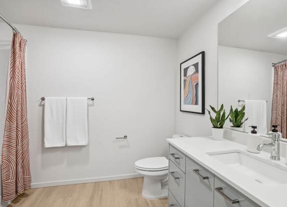 A bathroom with a toilet, sink, and mirror.