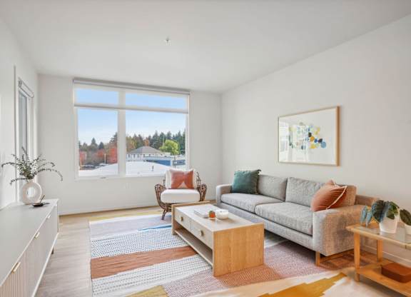 A living room with a grey couch, a coffee table, and a painting on the wall.