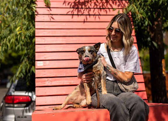 A woman is sitting on a red bench holding a dog.