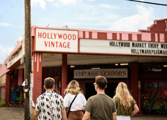A group of people are walking towards a Hollywood Vintage store.