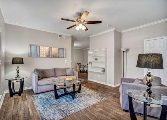 A living room with a couch, a coffee table, and a ceiling fan.