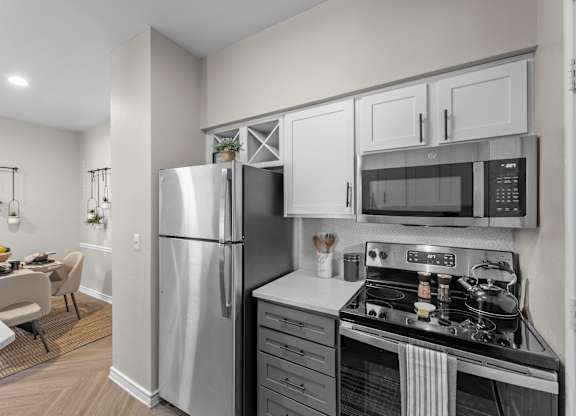 A modern kitchen with a refrigerator, microwave, and oven.