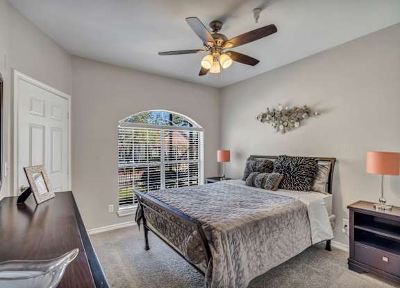 A bedroom with a bed, nightstand, and a ceiling fan.