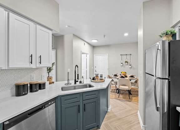 A kitchen with a black refrigerator and a dining table with chairs.