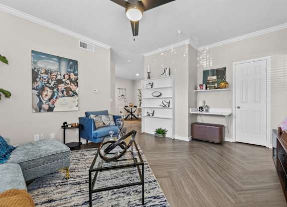 A living room with a blue couch and a painting on the wall.