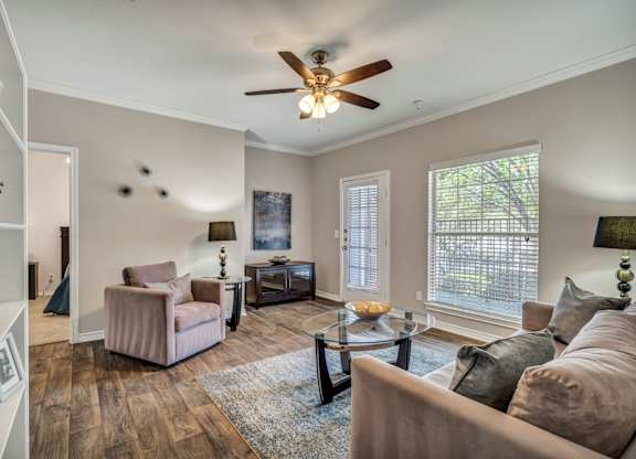 A living room with a brown couch and a ceiling fan.
