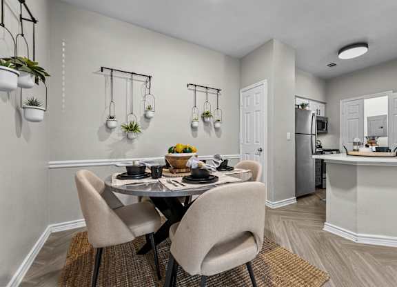 A dining room with a table set for two and a kitchen area in the background.