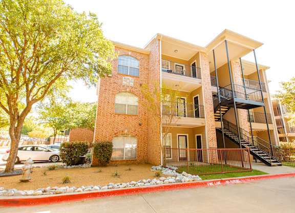 A red brick apartment building with a balcony on the second floor.