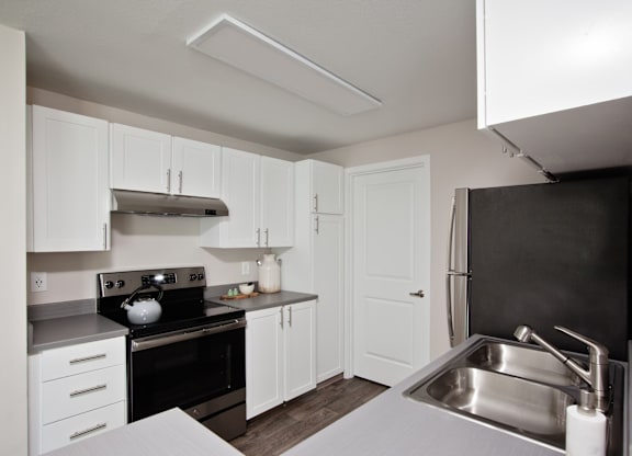 A kitchen with white cabinets and a black stove top.