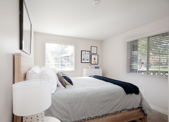 A bedroom with a bed, nightstand, and pictures on the wall.
