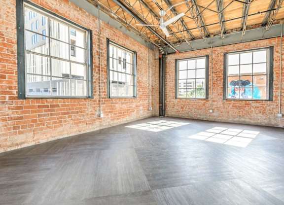 A large empty room with wooden floors and brick walls.