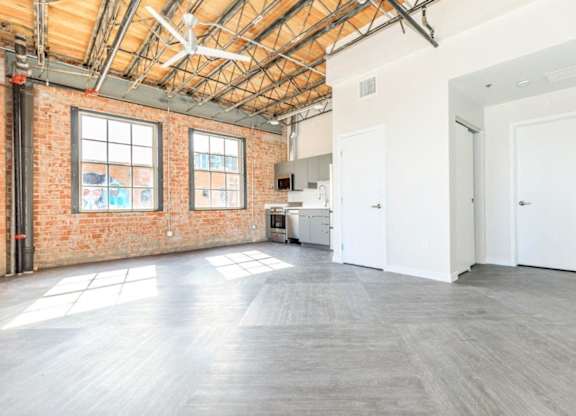 A large empty room with a brick wall and wooden ceiling.