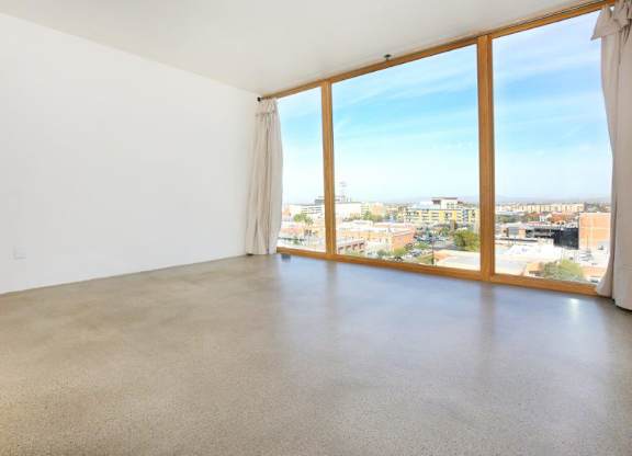 A large empty room with a view of the cityscape outside the window at Herbert Residential, Tucson