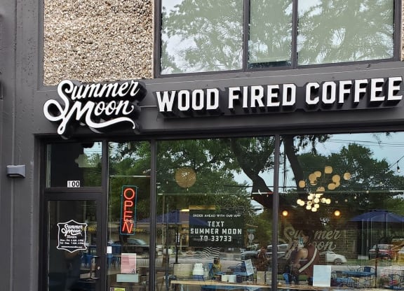 the outside of a coffee shop with blue tables and chairs