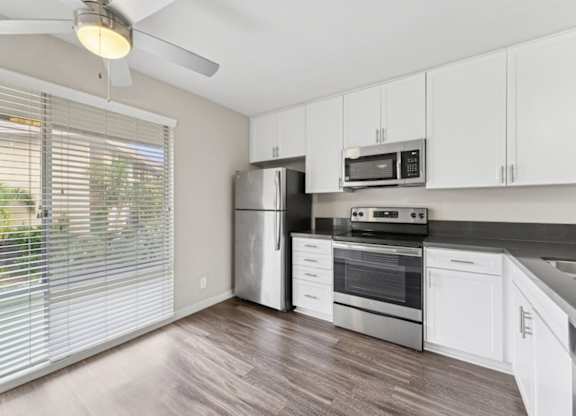A kitchen with white cabinets and a stainless steel refrigerator.