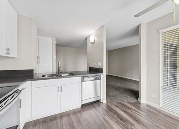 A kitchen with white cabinets and a wooden floor.