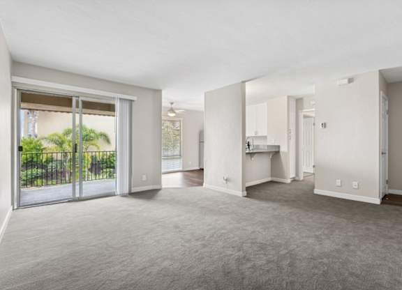 A spacious living room with a sliding glass door leading to a backyard.