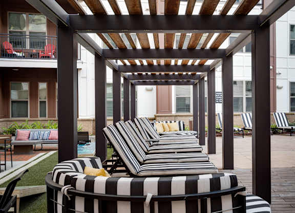 an outdoor lounge area with striped lounge chairs and a pergola