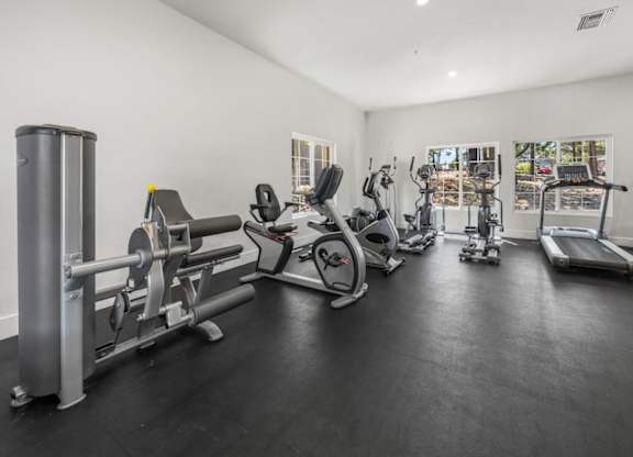 A spacious gym with a variety of equipment including treadmills, stationary bikes, and weight machines.