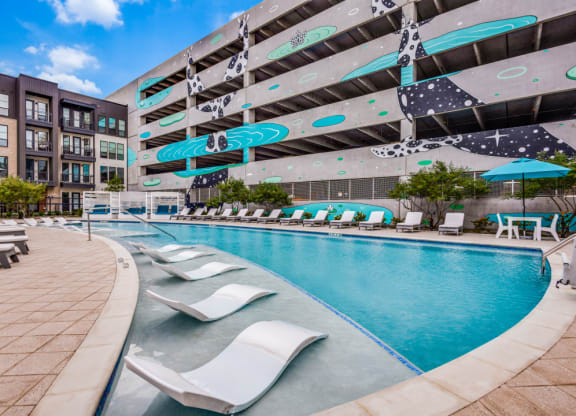 a swimming pool with lounge chairs and a building in the background