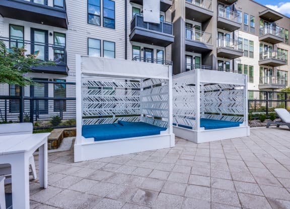 two hammocks on a patio in front of an apartment building