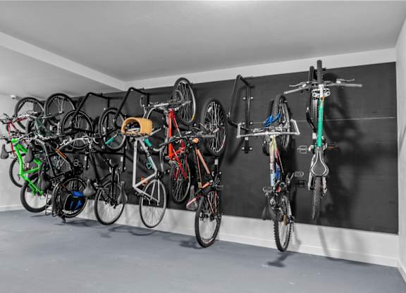 A wall-mounted bike rack with many bikes hanging on it.