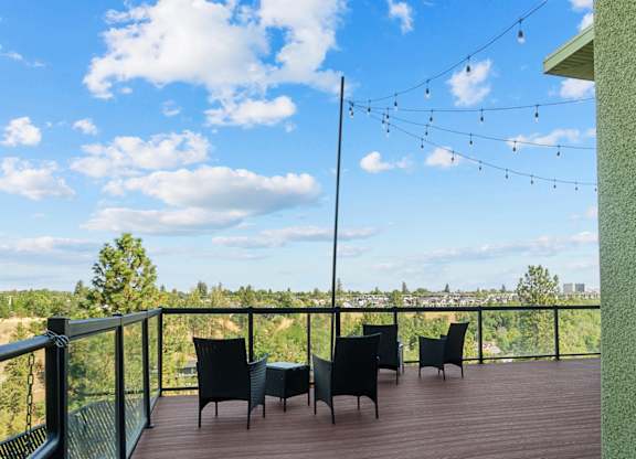 A balcony with chairs and a table overlooking a landscape.