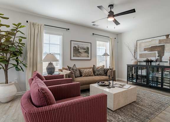 A living room with a red couch and a ceiling fan.