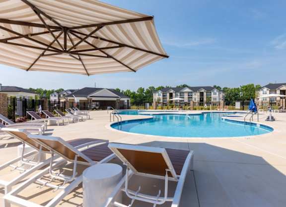 A sunny day at the pool with chairs and umbrellas.