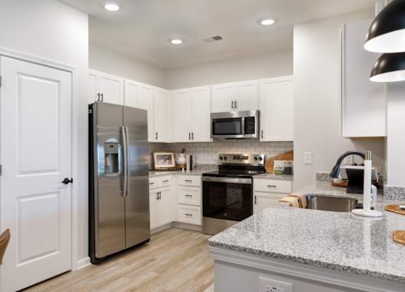 A kitchen with a refrigerator, oven, and sink.