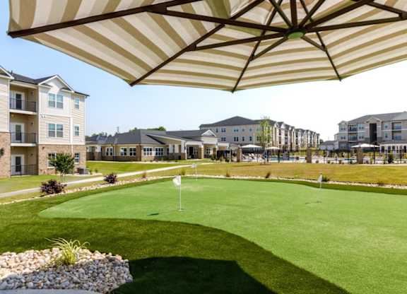 A golf course is surrounded by apartment buildings.
