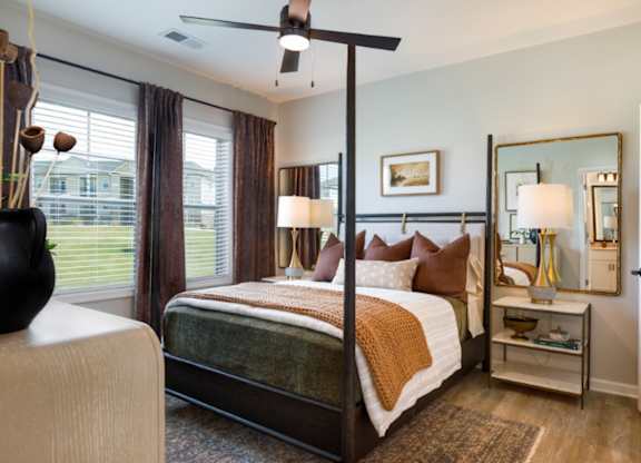 A bedroom with a four poster bed and a mirror on the wall.