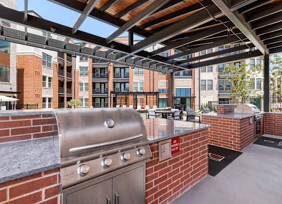 A patio with a grill and a brick wall.
