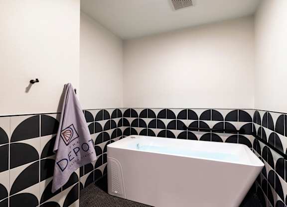 A white bathtub sits in a bathroom with black and white tiles.