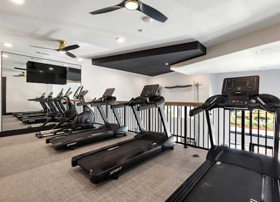 A gym with treadmills and a television.