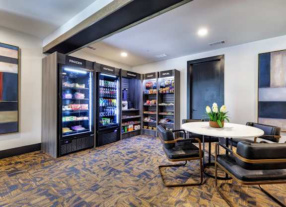 A room with a table, chairs and a frozen yogurt machine.
