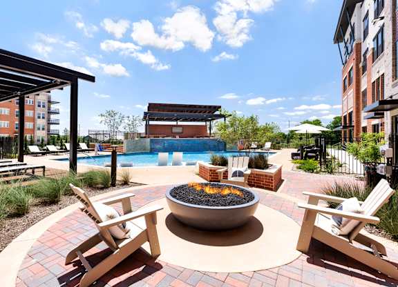 A patio with a fire pit and chairs.