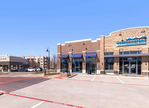 A street view of a shopping area with a blue sign on the building.