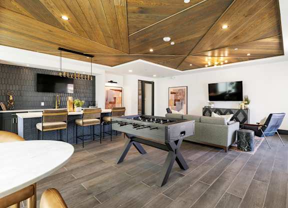 A modern living room with a wooden ceiling and a white dining table.