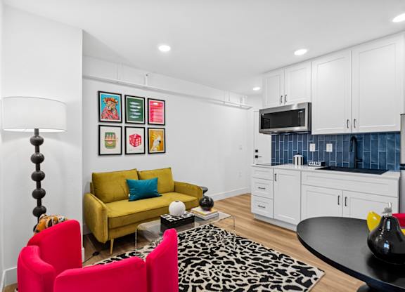 A living room with a yellow couch and red chairs.