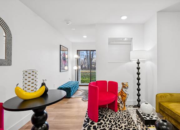 A living room with a yellow couch, a red chair, and a black table with a banana on it.