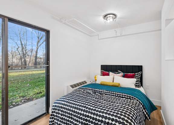 A bedroom with a bed and a window overlooking a field.