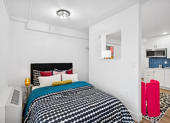 A bedroom with a black and white bedspread and a white bed.