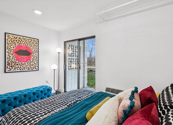 A bedroom with a blue bed and a leopard print picture on the wall.