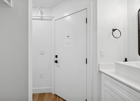 A white bathroom with a sink and a door.