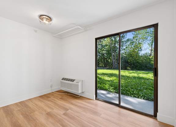 A room with a sliding glass door leading to a garden.