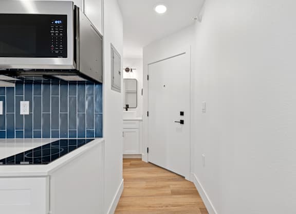 A kitchen with a blue backsplash and white cabinets.