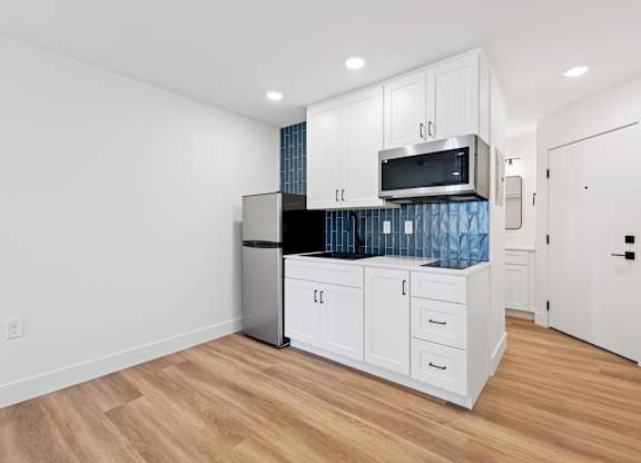 A kitchen with white cabinets and a stainless steel refrigerator.